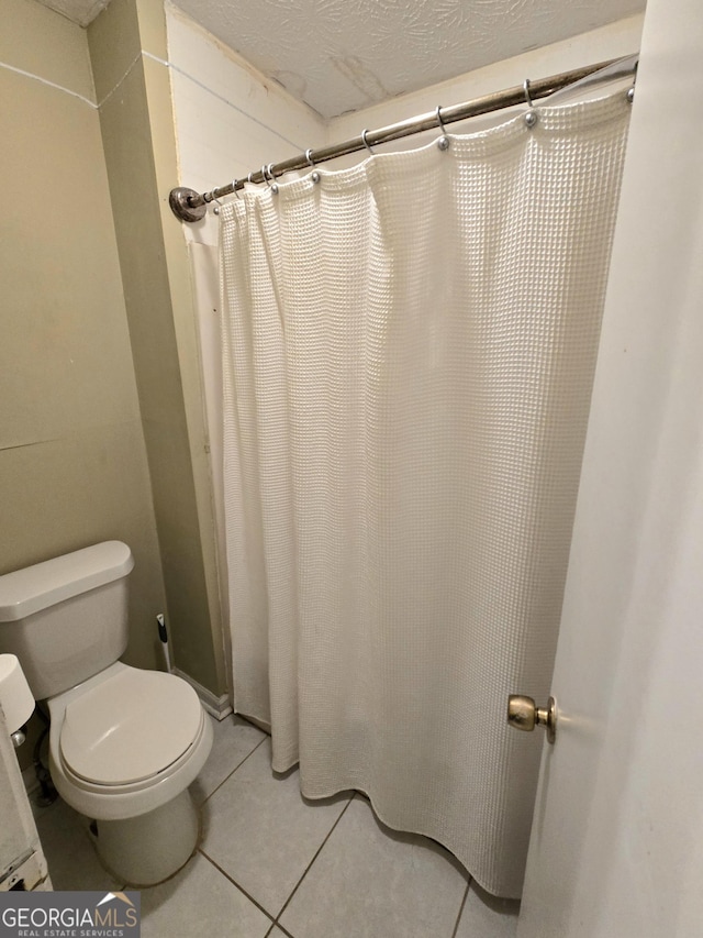 bathroom with tile patterned floors, curtained shower, toilet, and a textured ceiling