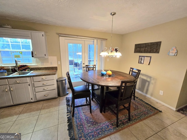 dining space with a textured ceiling, a notable chandelier, light tile patterned floors, and sink