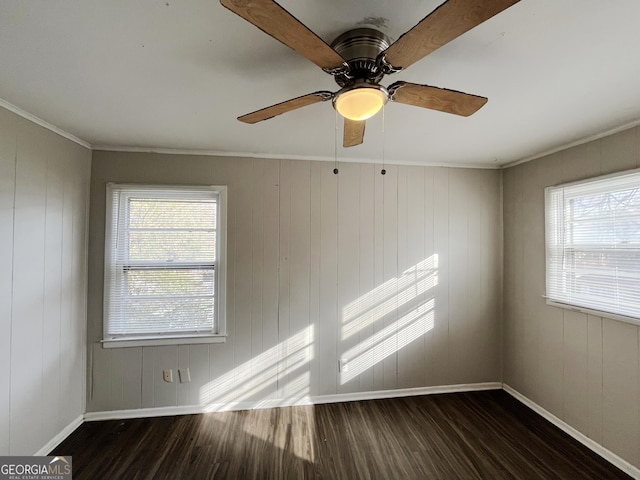 empty room with ceiling fan, crown molding, and wood walls