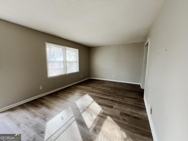 unfurnished room with dark hardwood / wood-style flooring and a textured ceiling