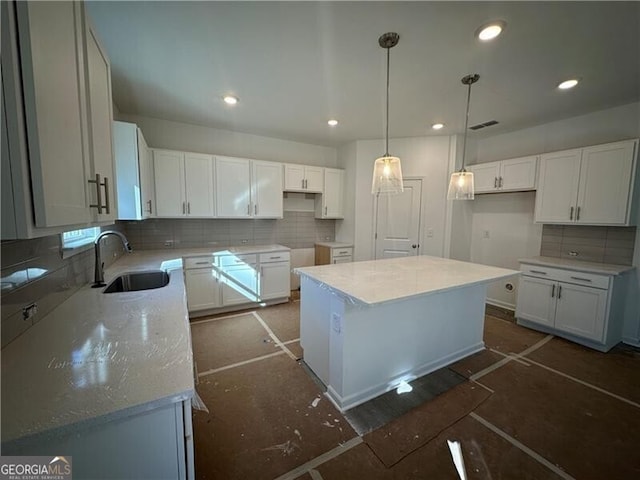 kitchen with sink, a kitchen island, backsplash, pendant lighting, and white cabinets