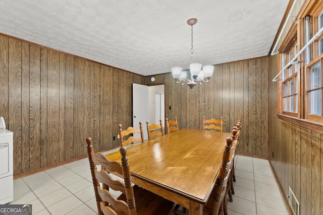 dining room with light tile patterned flooring, wooden walls, and a textured ceiling