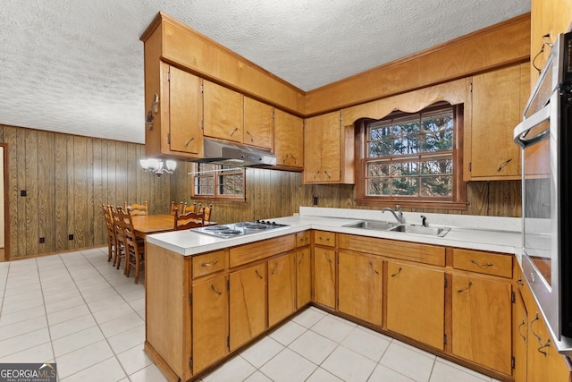 kitchen with light tile patterned flooring, white cooktop, sink, and wood walls