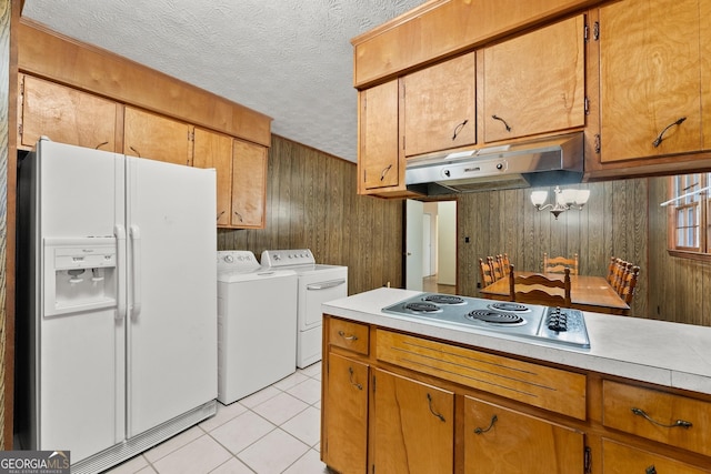 kitchen featuring wooden walls, white fridge with ice dispenser, washing machine and clothes dryer, and electric stovetop