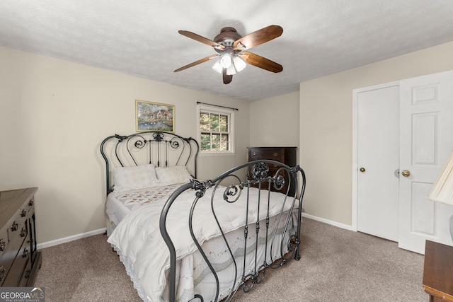 carpeted bedroom with ceiling fan and a textured ceiling