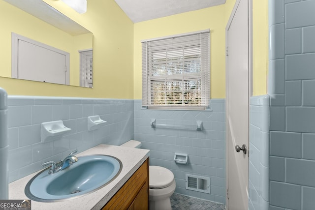 bathroom featuring vanity, toilet, tile walls, and a textured ceiling