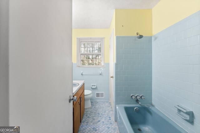 bathroom with tile walls, tile patterned flooring, vanity, a textured ceiling, and toilet