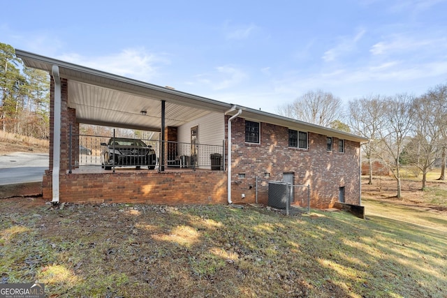 back of house featuring a carport, a yard, and central air condition unit