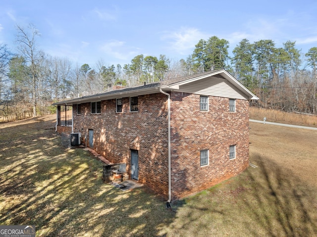 view of side of property with a yard and central AC