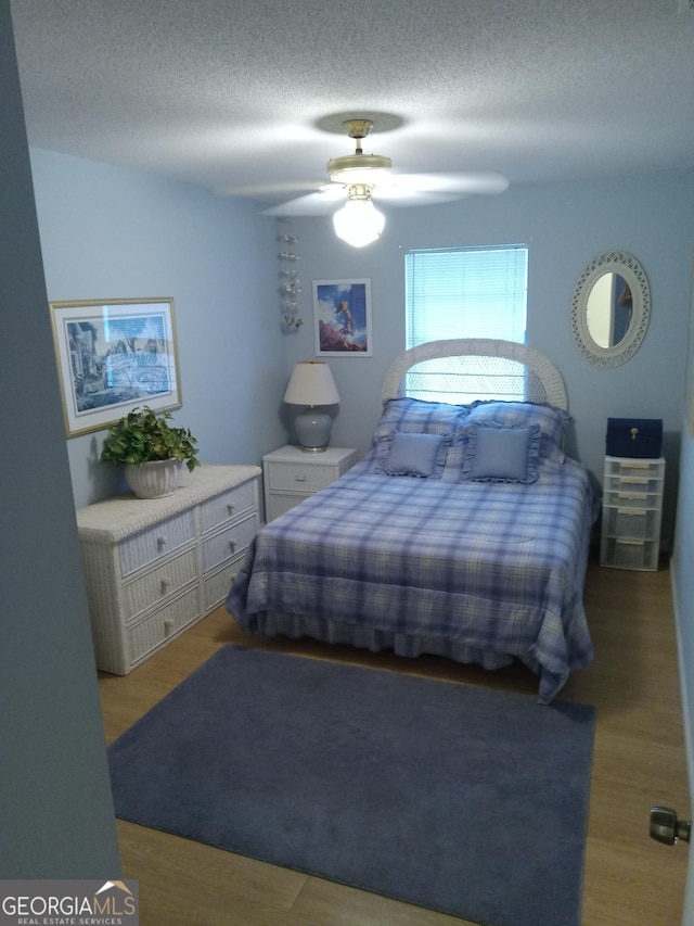 bedroom featuring ceiling fan, light hardwood / wood-style flooring, and a textured ceiling