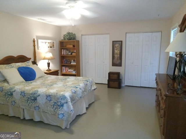 bedroom with ceiling fan, two closets, and concrete flooring