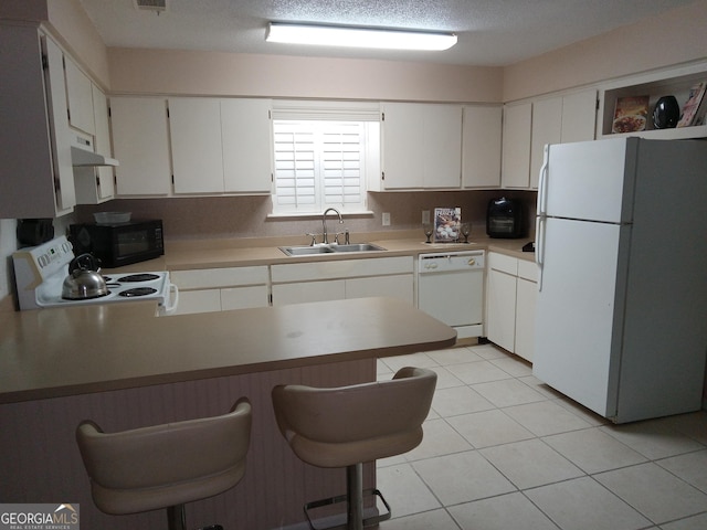 kitchen with white appliances, light tile patterned floors, a breakfast bar, sink, and white cabinetry