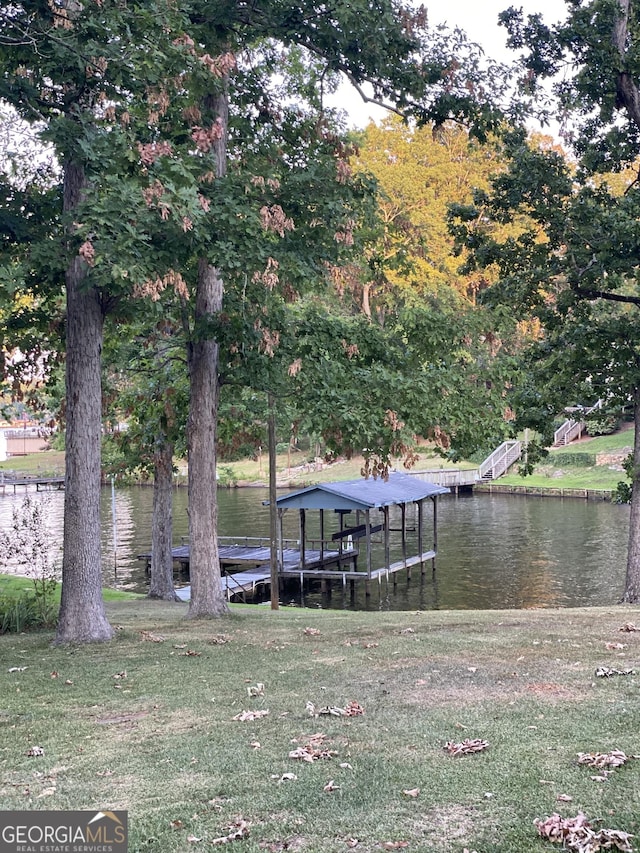 view of dock with a yard and a water view