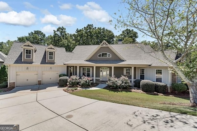 view of front facade featuring a front lawn, covered porch, and a garage