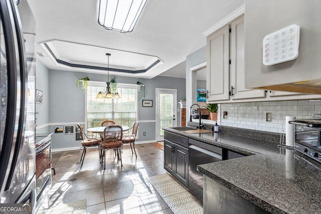 kitchen with black fridge, a raised ceiling, sink, a notable chandelier, and dishwasher