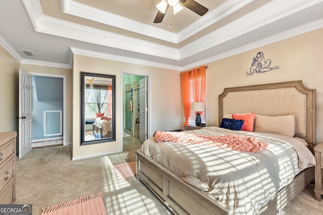 carpeted bedroom with a tray ceiling, ensuite bathroom, ceiling fan, and ornamental molding