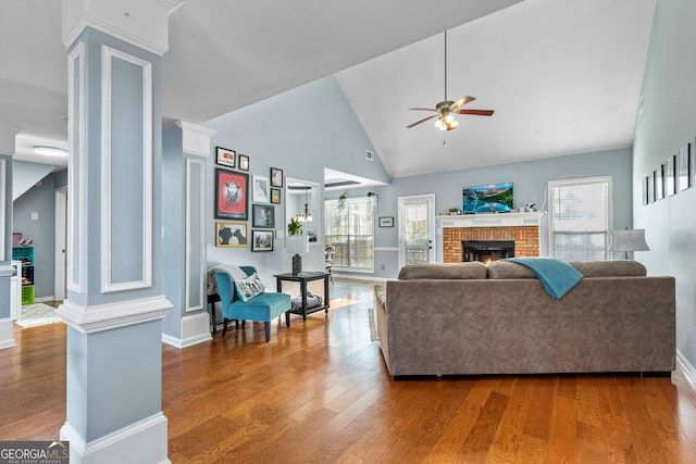 living room featuring ornate columns, vaulted ceiling, ceiling fan, wood-type flooring, and a fireplace