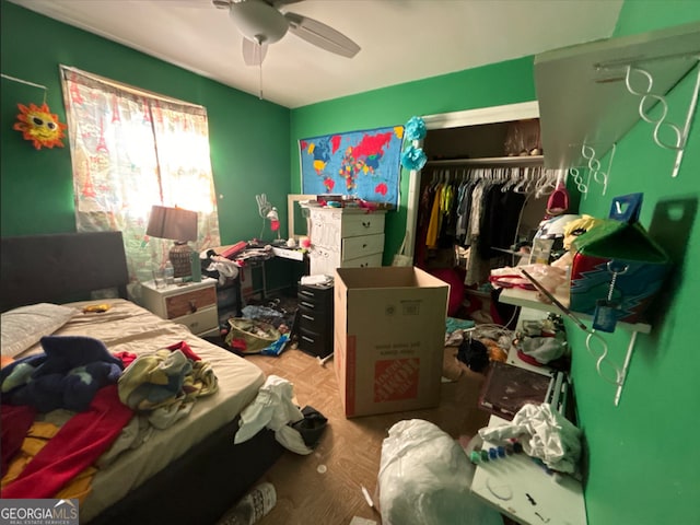 bedroom featuring ceiling fan, a closet, and parquet flooring