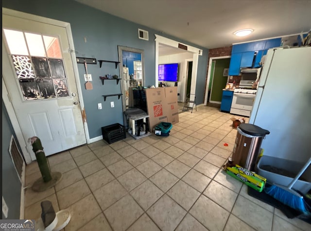 kitchen featuring tile patterned floors, white appliances, and blue cabinets