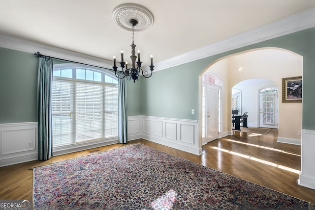 dining area with a chandelier, wood-type flooring, and ornamental molding