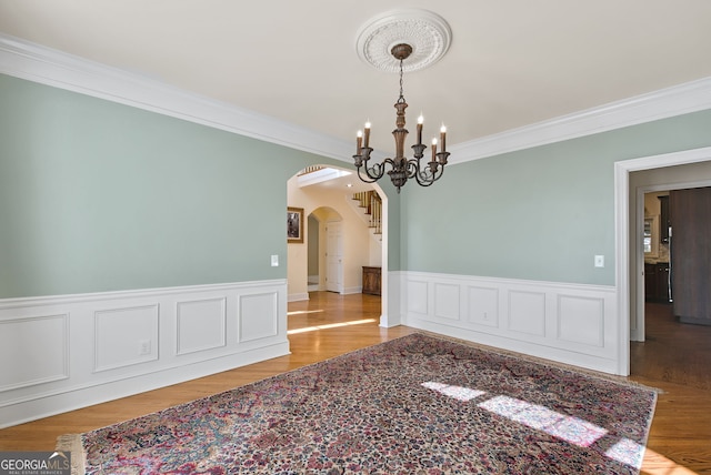 empty room with ornamental molding and an inviting chandelier