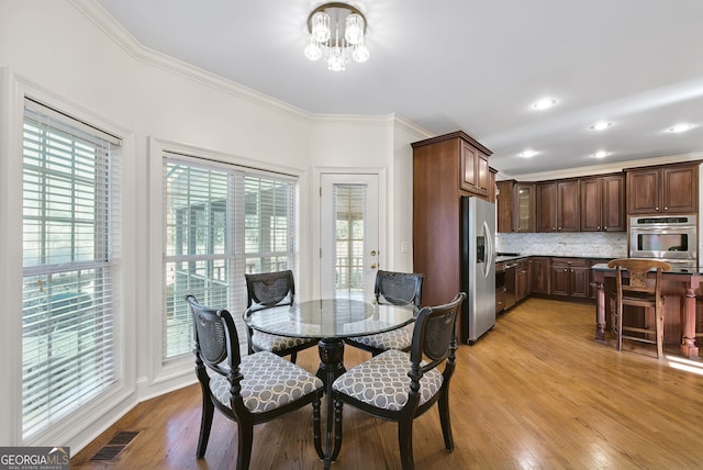 dining room featuring a chandelier, ornamental molding, and light hardwood / wood-style flooring