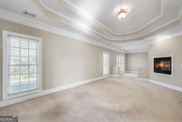 unfurnished living room with a tray ceiling, crown molding, and light colored carpet