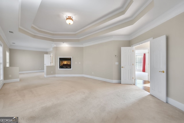 unfurnished living room with ornamental molding, light carpet, and a tray ceiling