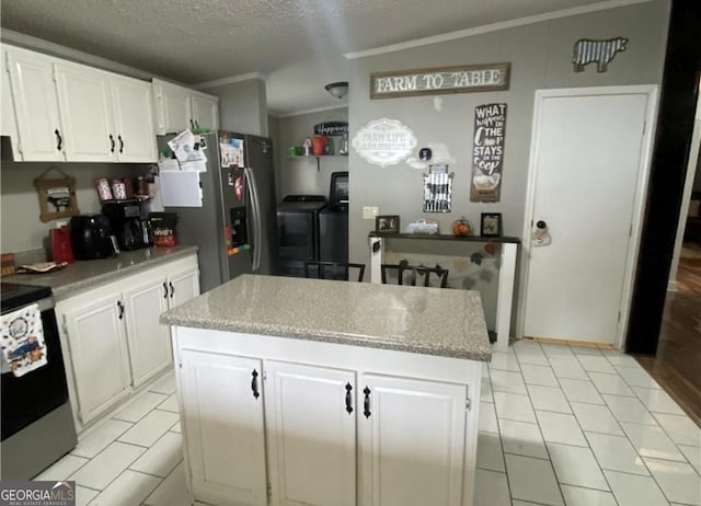 kitchen with white cabinets, range with electric stovetop, washing machine and dryer, a textured ceiling, and a kitchen island