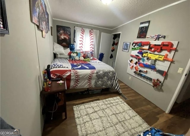 bedroom with a textured ceiling, dark wood-type flooring, and crown molding