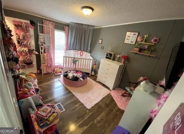 bedroom featuring a textured ceiling, crown molding, a nursery area, and dark hardwood / wood-style floors