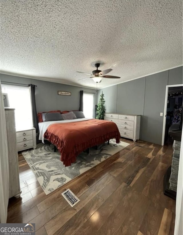 bedroom with hardwood / wood-style flooring, ceiling fan, and a textured ceiling