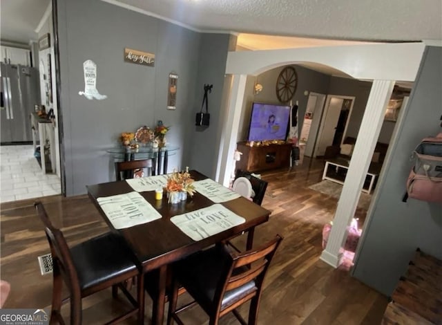 dining area with dark hardwood / wood-style flooring, ornamental molding, and a textured ceiling