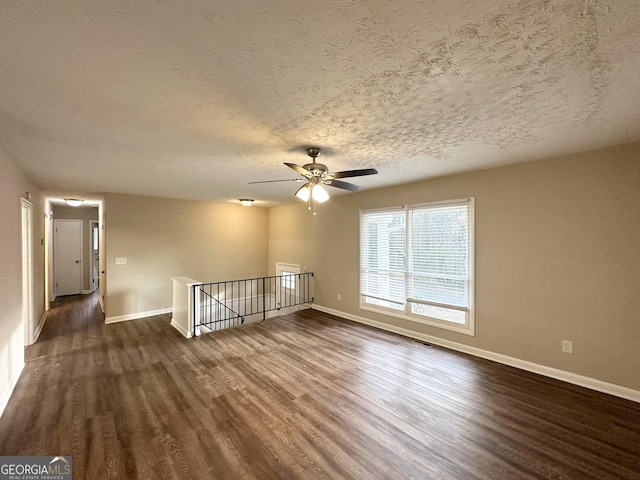 empty room with a textured ceiling, ceiling fan, and dark wood-type flooring