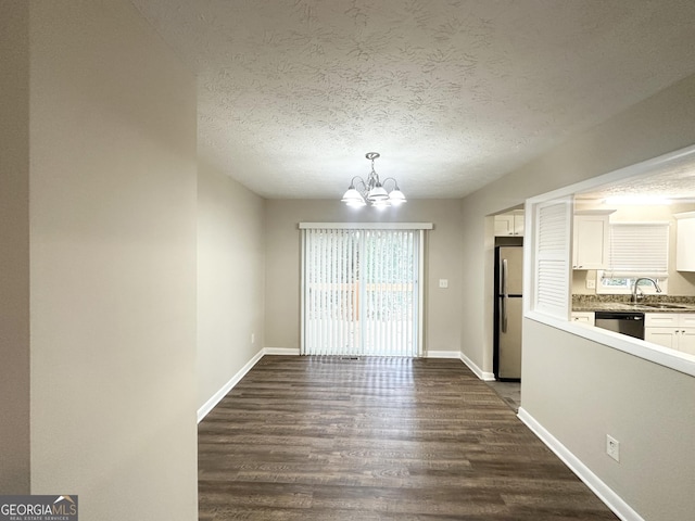 unfurnished dining area featuring a textured ceiling, dark wood-type flooring, a notable chandelier, and sink