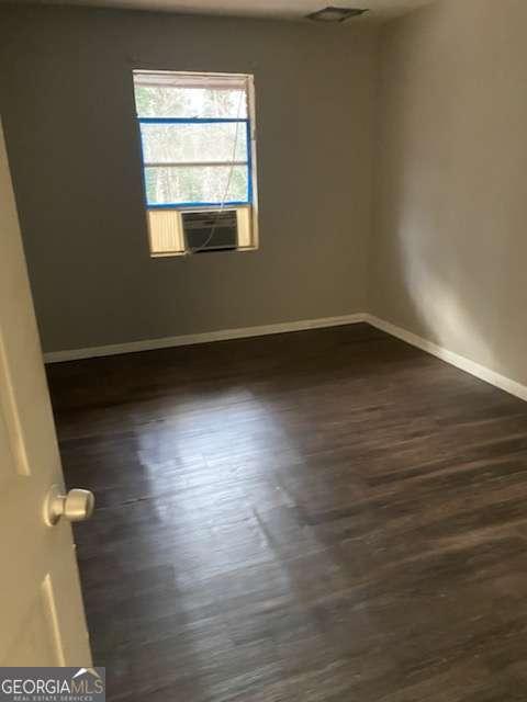 empty room with cooling unit and dark hardwood / wood-style flooring