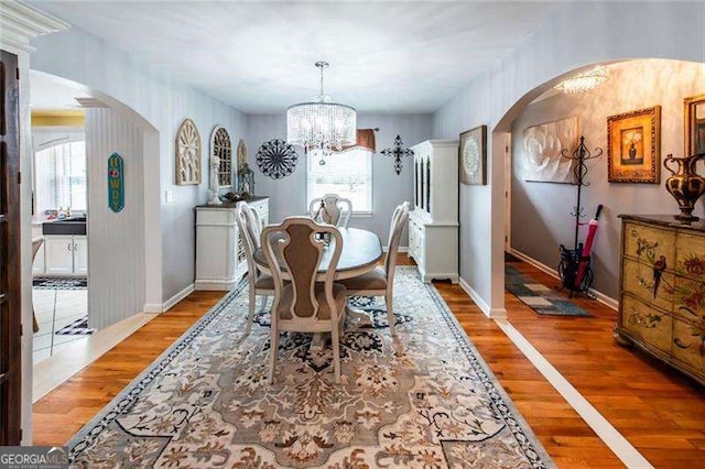 dining space with hardwood / wood-style floors and an inviting chandelier