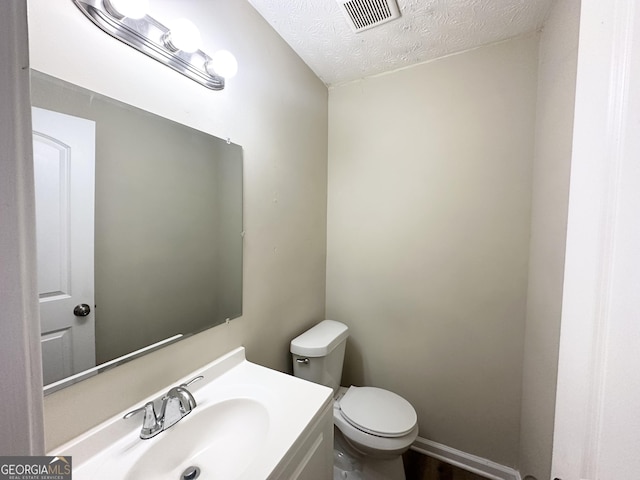 bathroom with vanity, a textured ceiling, and toilet