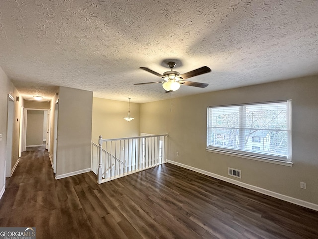 unfurnished room featuring a textured ceiling, dark hardwood / wood-style flooring, and ceiling fan