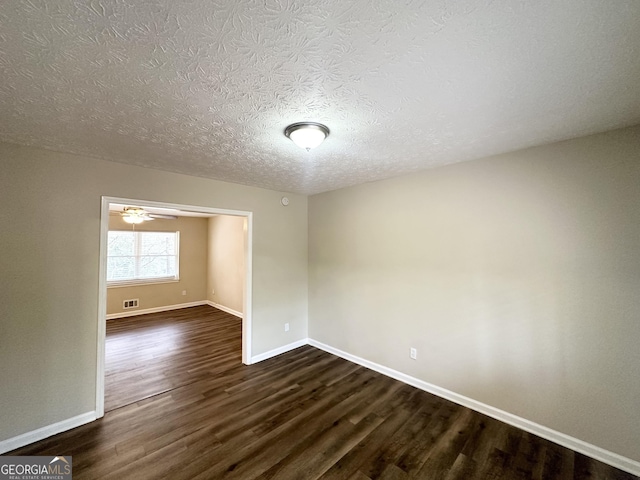 empty room featuring a textured ceiling, dark hardwood / wood-style flooring, and ceiling fan