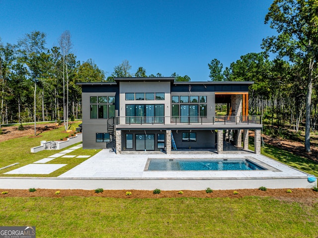 back of house featuring a balcony, a patio area, and a lawn