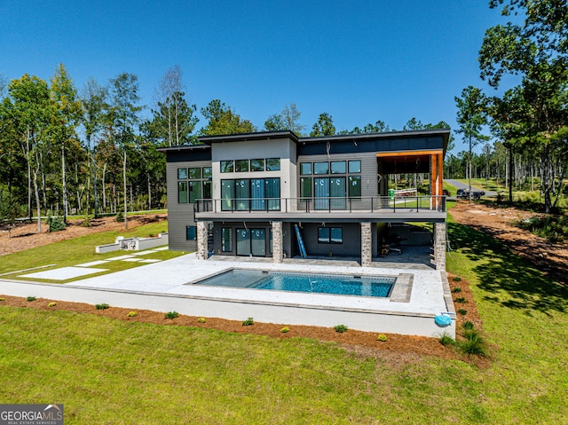 back of house with a balcony, a patio area, and a lawn