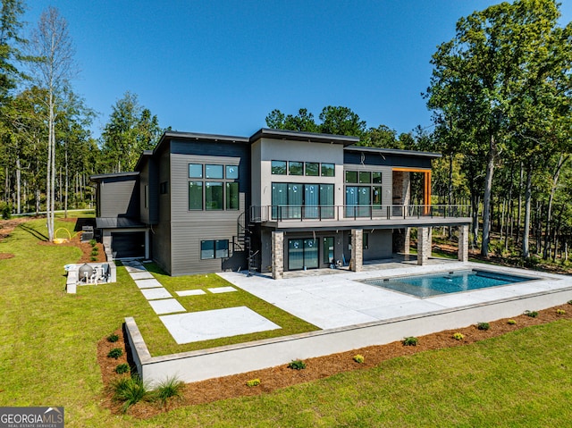 rear view of house featuring a balcony, a yard, and a patio