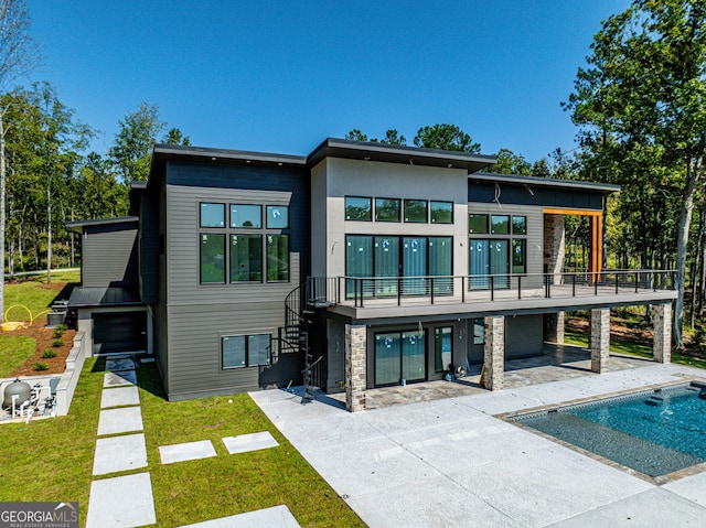 back of house featuring a balcony, a patio area, and a lawn