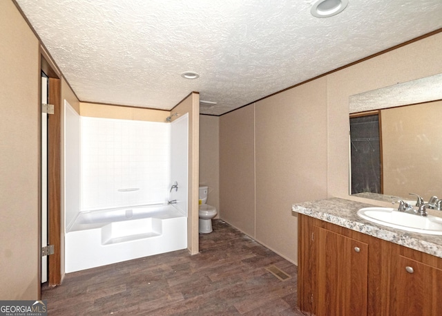 full bathroom with vanity, hardwood / wood-style floors, a textured ceiling, toilet, and shower / bathing tub combination