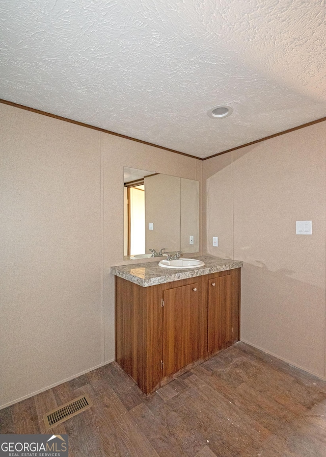 interior space with wood-type flooring, vanity, a textured ceiling, and crown molding