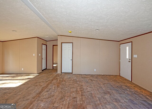 spare room featuring a textured ceiling, wood-type flooring, and vaulted ceiling