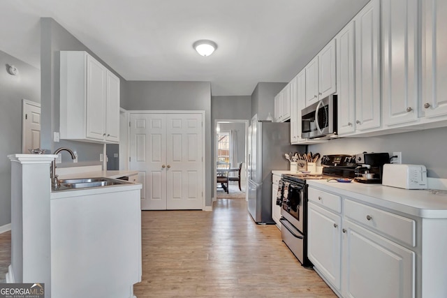 kitchen with white cabinetry, sink, light wood-type flooring, and appliances with stainless steel finishes