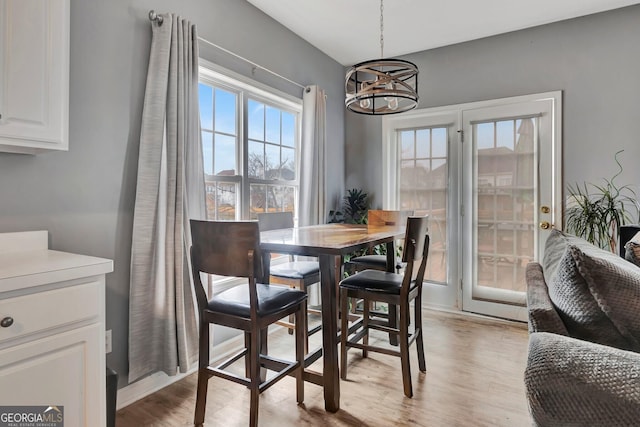 dining area with light wood-type flooring and an inviting chandelier