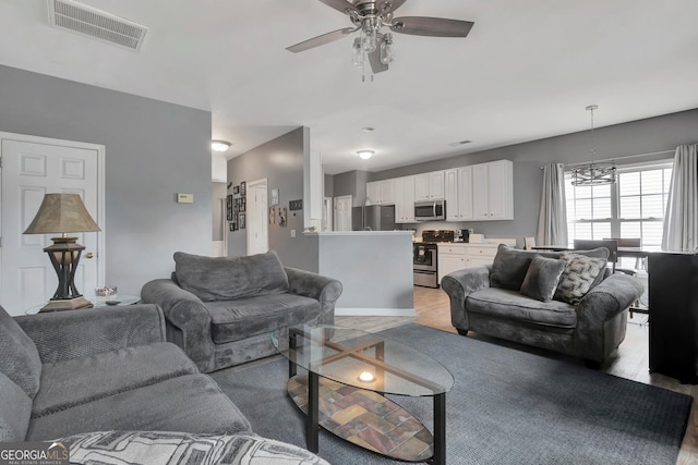 living room with light hardwood / wood-style flooring and ceiling fan with notable chandelier